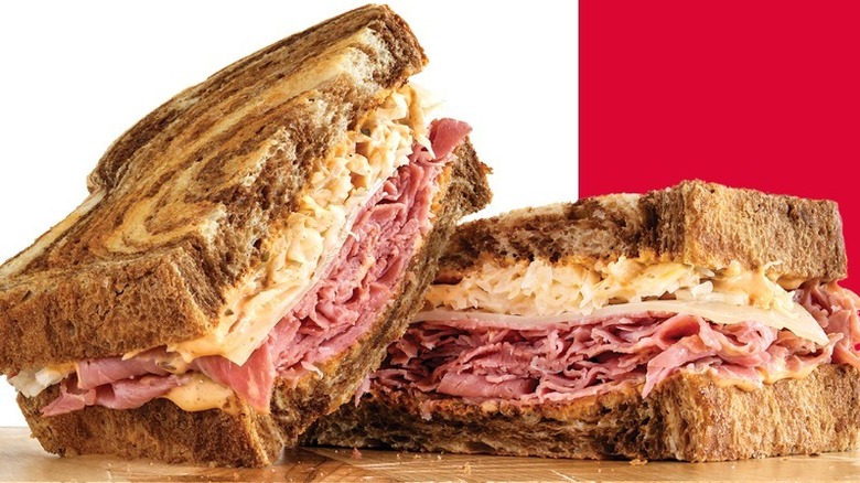 A sliced Reuben sandwich in front of a white and red background