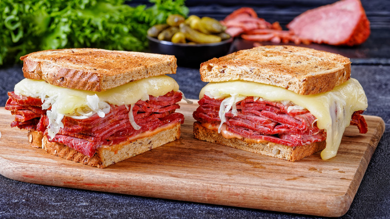 A sliced corned beef sandwich on a wooden cutting board