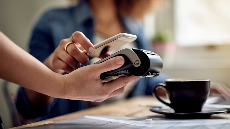 Person paying at a table by tapping their card