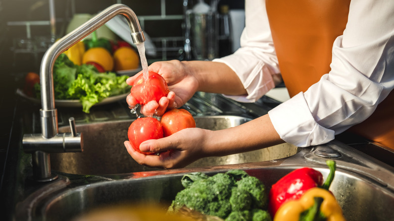 Red tomatoes being washing in a sink