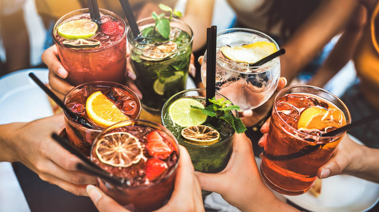 friends toasting with multiple different cocktails