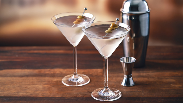 two martinis on a bar with a shaker and jigger