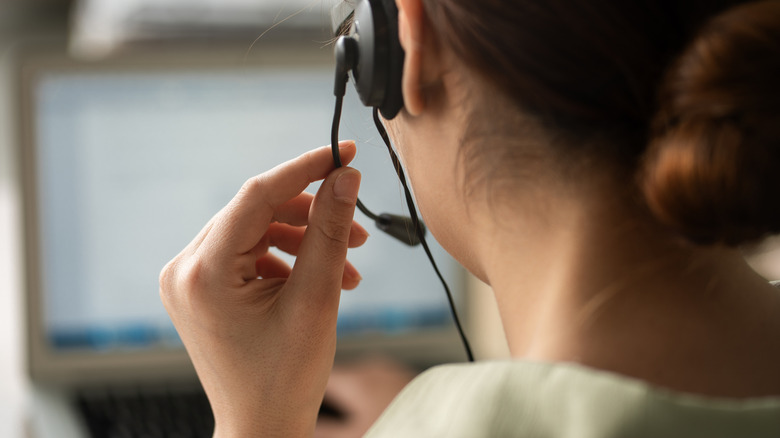 back of woman's head, wearing headset on computer