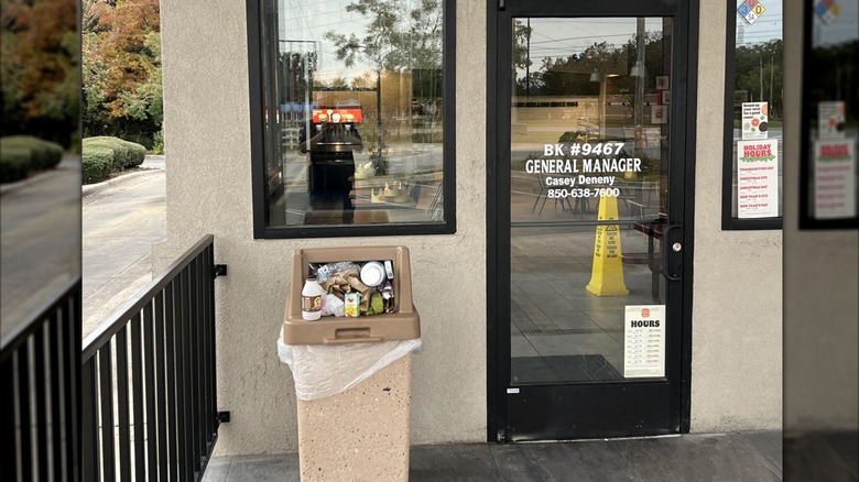 Mirrored image of overflowing trash can outside burger king