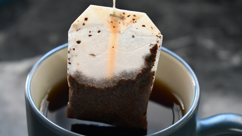 Used tea bag dipping into a mug
