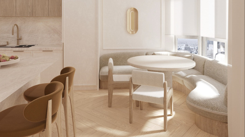 A neutral and sculptural kitchen design with an upholstered breakfast nook near the window