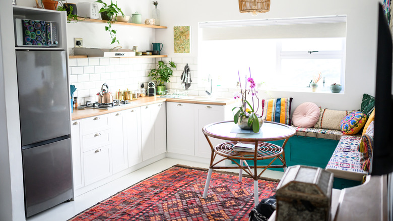 A quaint and adorable kitchen with a seating bench in the corner and a small glass bistro table