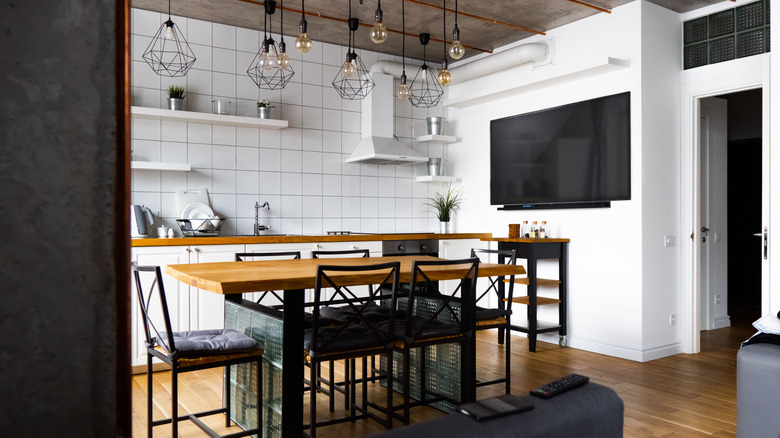 A small kitchen and living room shared space with a nice dining table acting as a divider in the room