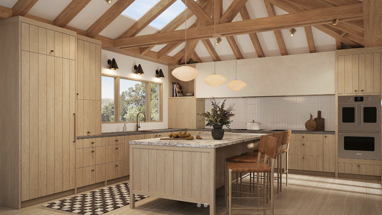 A spacious beige kitchen with light wood ceiling beams and a large kitchen island in the center of the room with stools