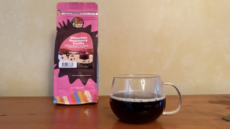 Glass of coffee on wooden table with bag of chocolate raspberry truffle coffee