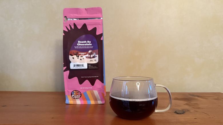 Glass of coffee on wooden table with bag of death by chocolate coffee