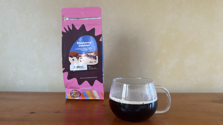 Glass of coffee on wooden table with bag of blueberry cobbler coffee