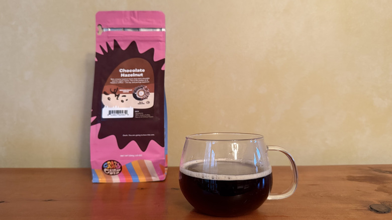 Glass of coffee on wooden table with bag of chocolate hazelnut coffee