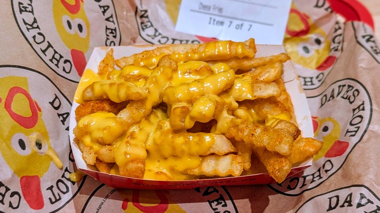 A paper container of cheese fries on Dave's Hot Chicken-branded paper