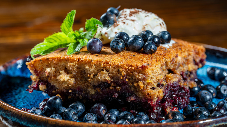 blueberries cobbler with fresh blueberries and a scoop of vanilla ice cream served on a blue plate