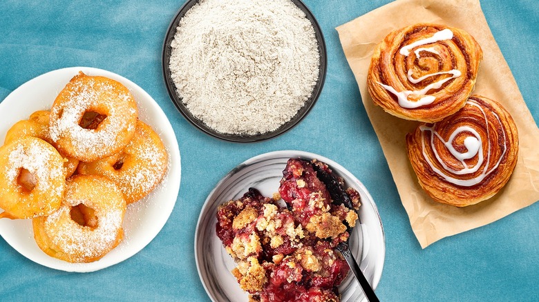 donuts with powdered sugar, flour, cinnamon rolls, and cobbler on plates with a blue background