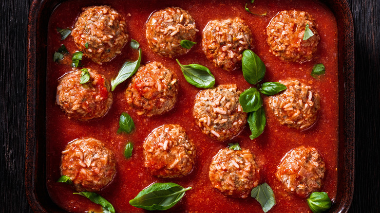 tray of porcupine meatballs garnished with basil on wooden table