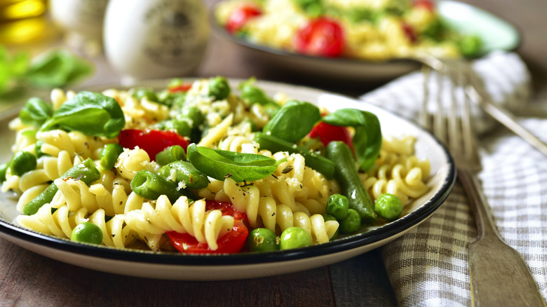 pasta primavera in a bowl next to cutlery and napkin