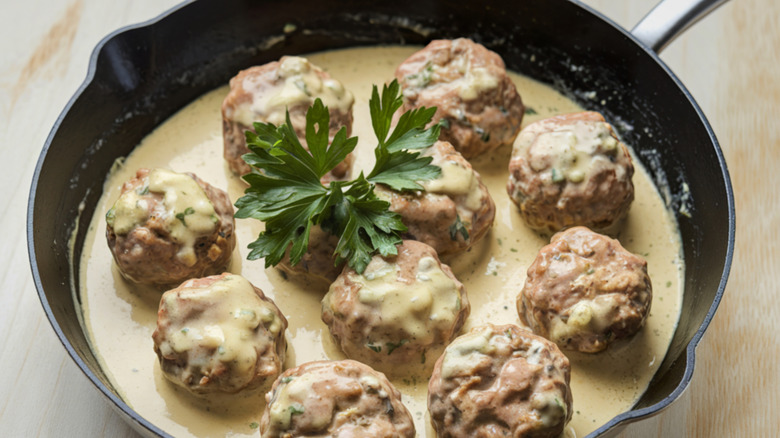 Swedish meatballs with a cream sauce and garnish in a skillet