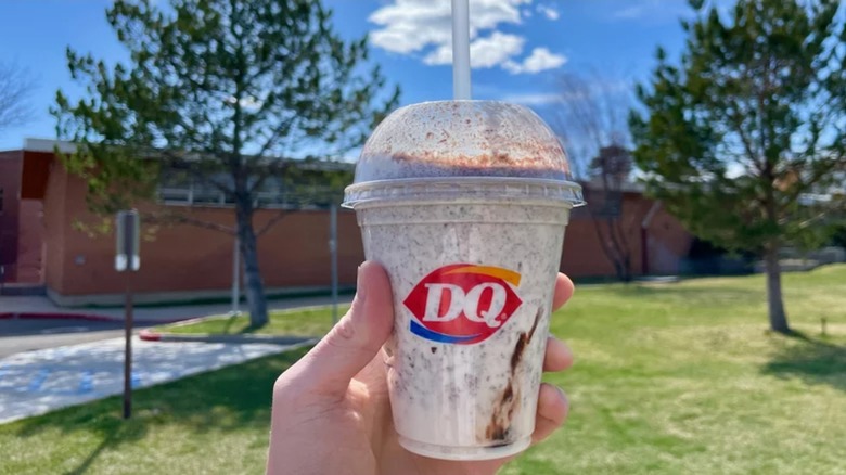 Hand holding DQ S'mores shake outdoors