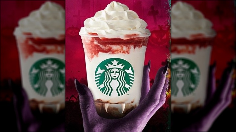 Purple hand with long black nails holding a Frappula with fangs