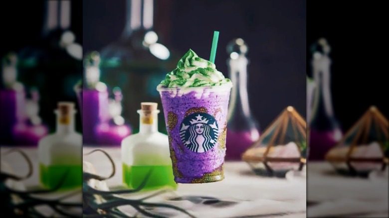 Witch's Brew Frappuccino floating through the air with a background of witch's potion items
