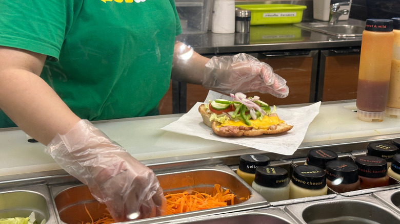 Close up of Subway Sandwich Artist making sandwich behind counter