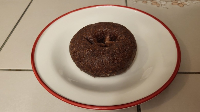 A chocolate cake donut on a white and red plate.