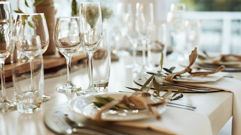 Formally laid out dining table with plates, glasses, cutlery and napkins