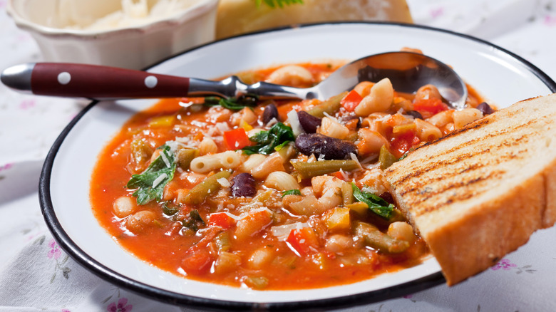 bowl of minestrone with bread on table