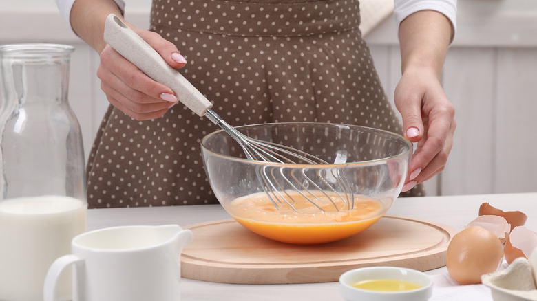 person whisking ingredients in bowl at counter