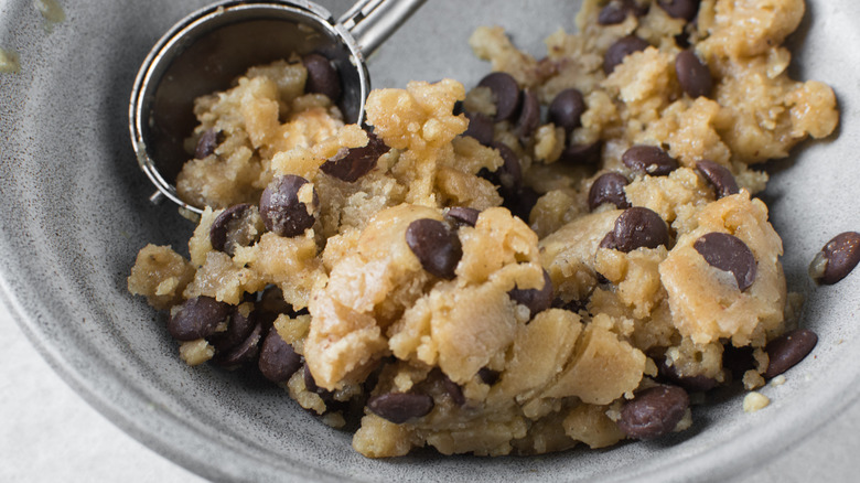 scooping chocolate chip cookie dough in bowl