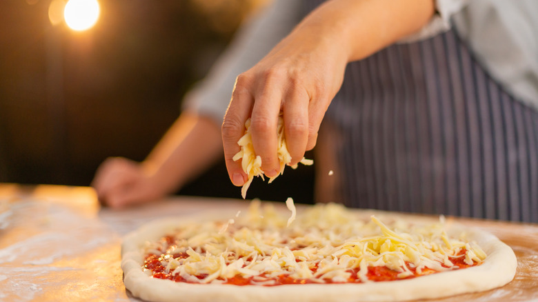 Hand sprinkling cheese on pizza
