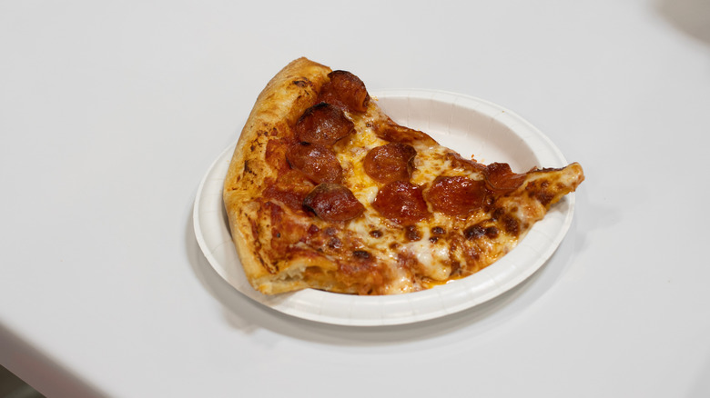 Slice of Costco pizza on white plate on table