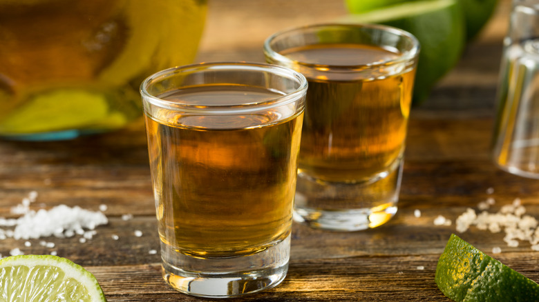 Reposado tequila shots on wooden table with lime