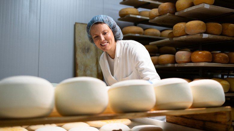 Woman in white lab coat and hair net surrounded by mozzarella