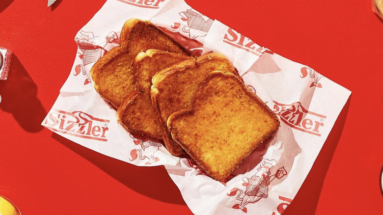 New Sizzler logo printed on deli paper underneath slices of toast.