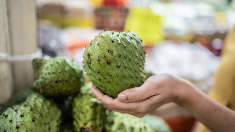 A soursop selected by a customer at a market