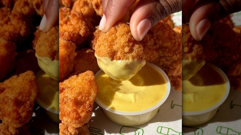 Close up of Shake Shack's crispy chicken bites being dipped in sauce.