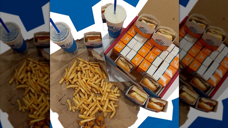 A box of white castle sliders with fries and drinks on a table