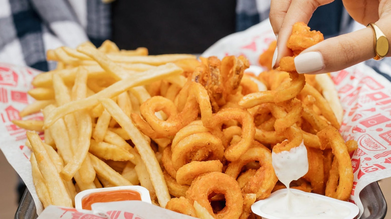 Someone holding a half-and-half order of curly and regular fries from Jack in the Box