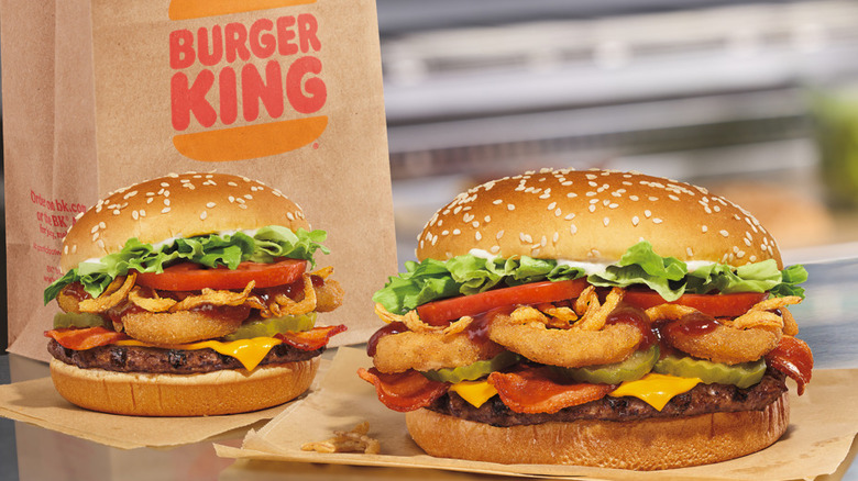 burger king whopper cheese burgers on brown papers with a burger king takeaway bag in the back