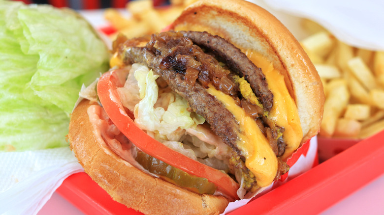In N Out Animal Style cheeseburger with fries on a red tray with lettuce on the side