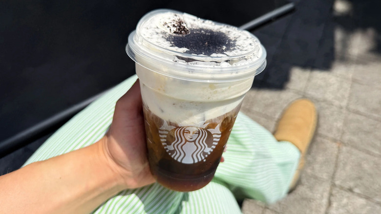 A hand holding a Starbucks cookies on top drink