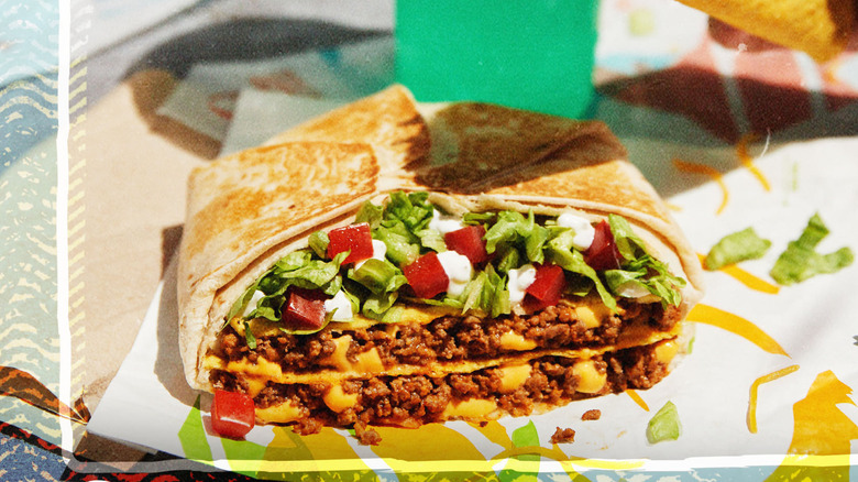 Taco Bell California Crunchwrap on parchment paper with a drink on the side