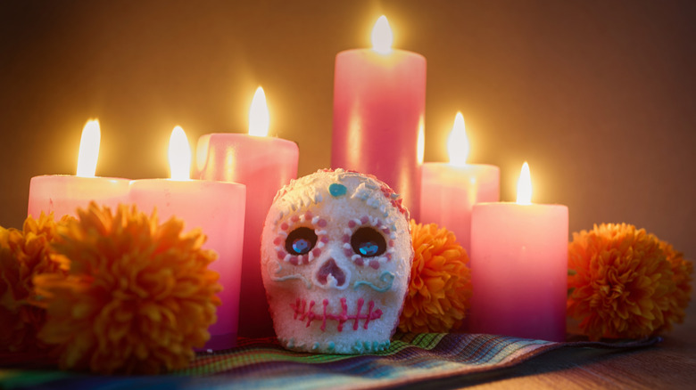 Sugar skull surrounded by candles and marigolds
