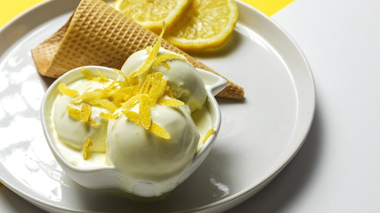lemon ice cream balls next to cone and lemon slices on white plate