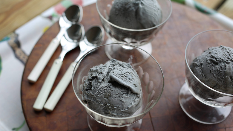 Three scoops of liquorice ice cream in glass bowls on table