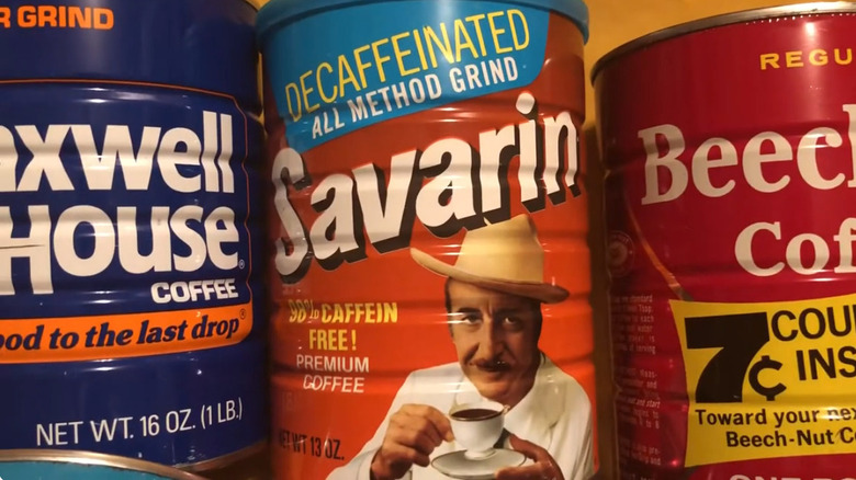 screencapture from a video about vintage coffee cans, showing a tin of decaffeinated Savarin coffee between a vintage Maxwell House can and one for Beech-Nut coffee