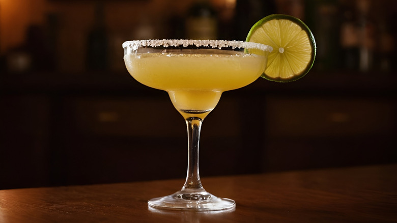 tequila daisy cocktail in a margarita glass with lime garnish